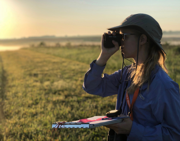 2018-19 American Fellow Jaime Coon looking through a lens at the horizon.