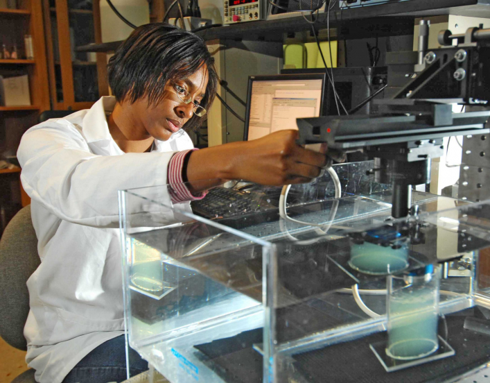 Woman in lab coat conducting research with lab equipment.